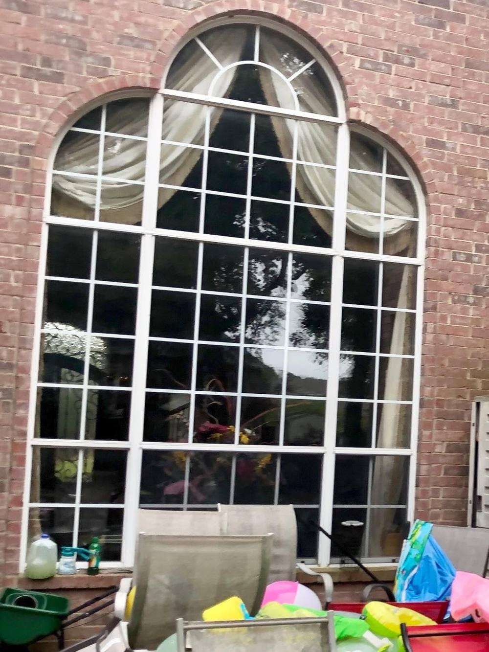 A tall arched window with white grid bars over every pane and fogged, aging glass.