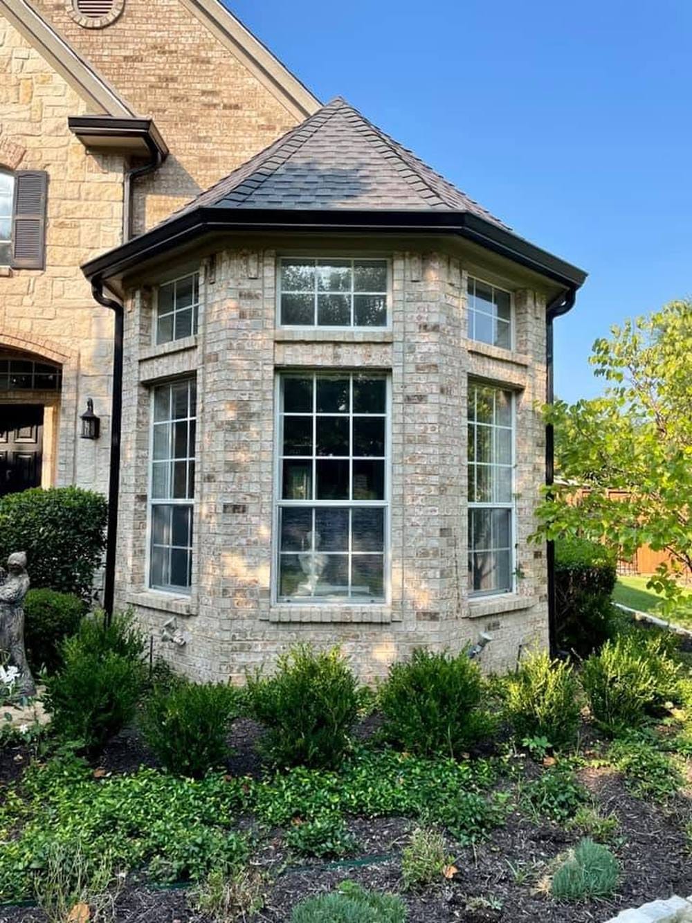 A two-story bay window with white frames and grids over the glass.