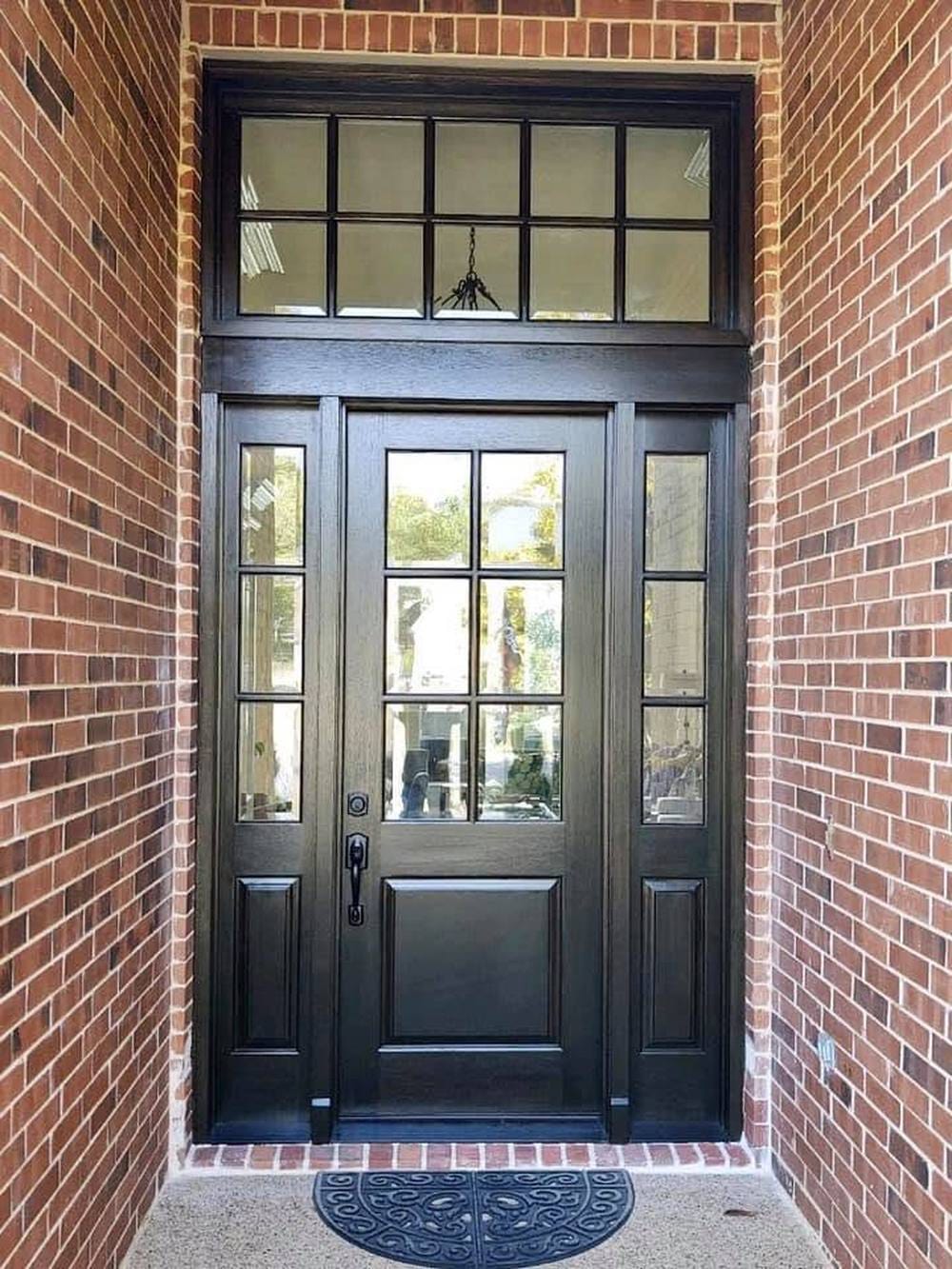 A stained wood entry door with clear glass, full-height sidelights and a divided transom above.