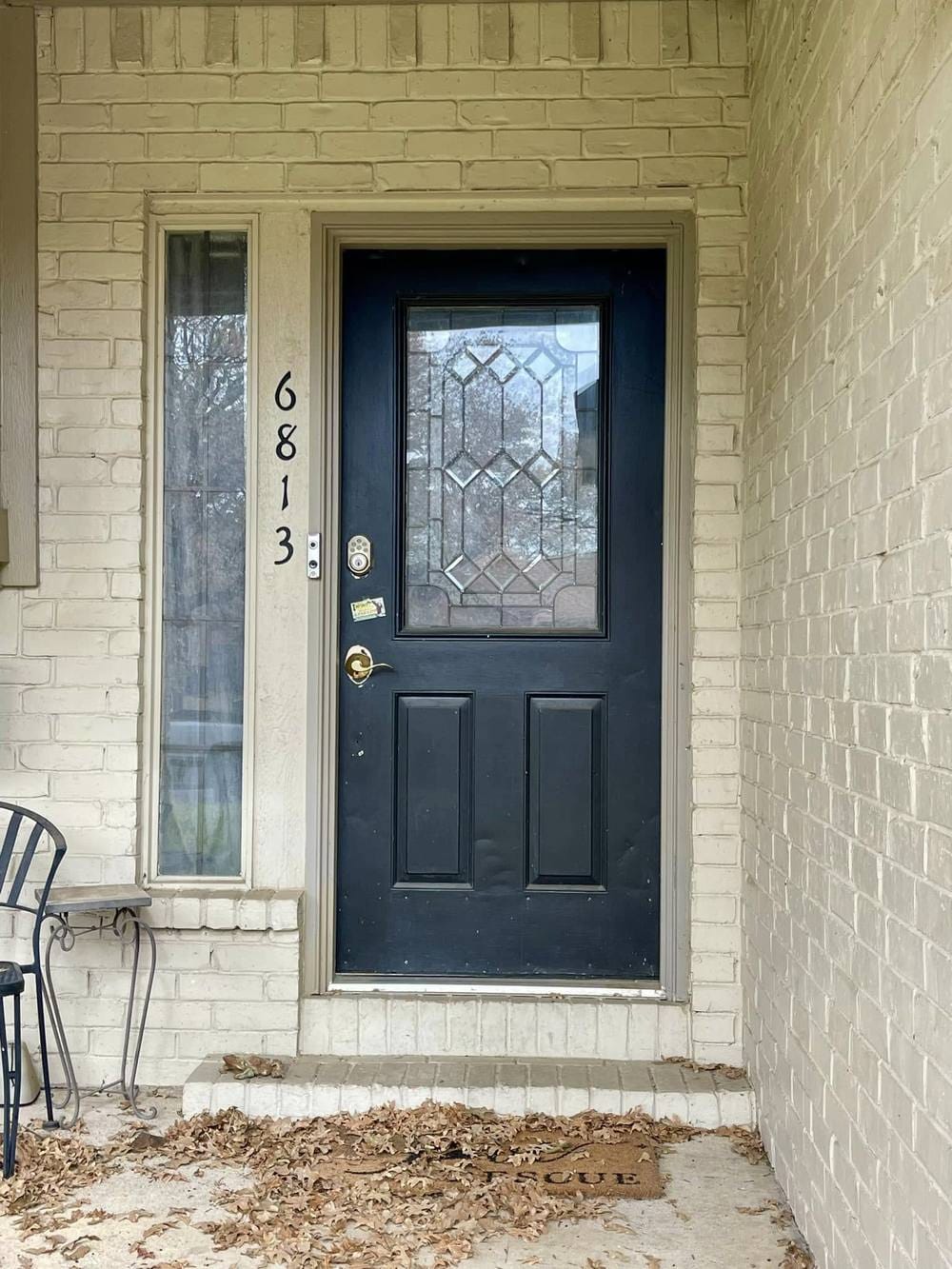 A dated navy entry door with leaded decorative glass and brass hardware.