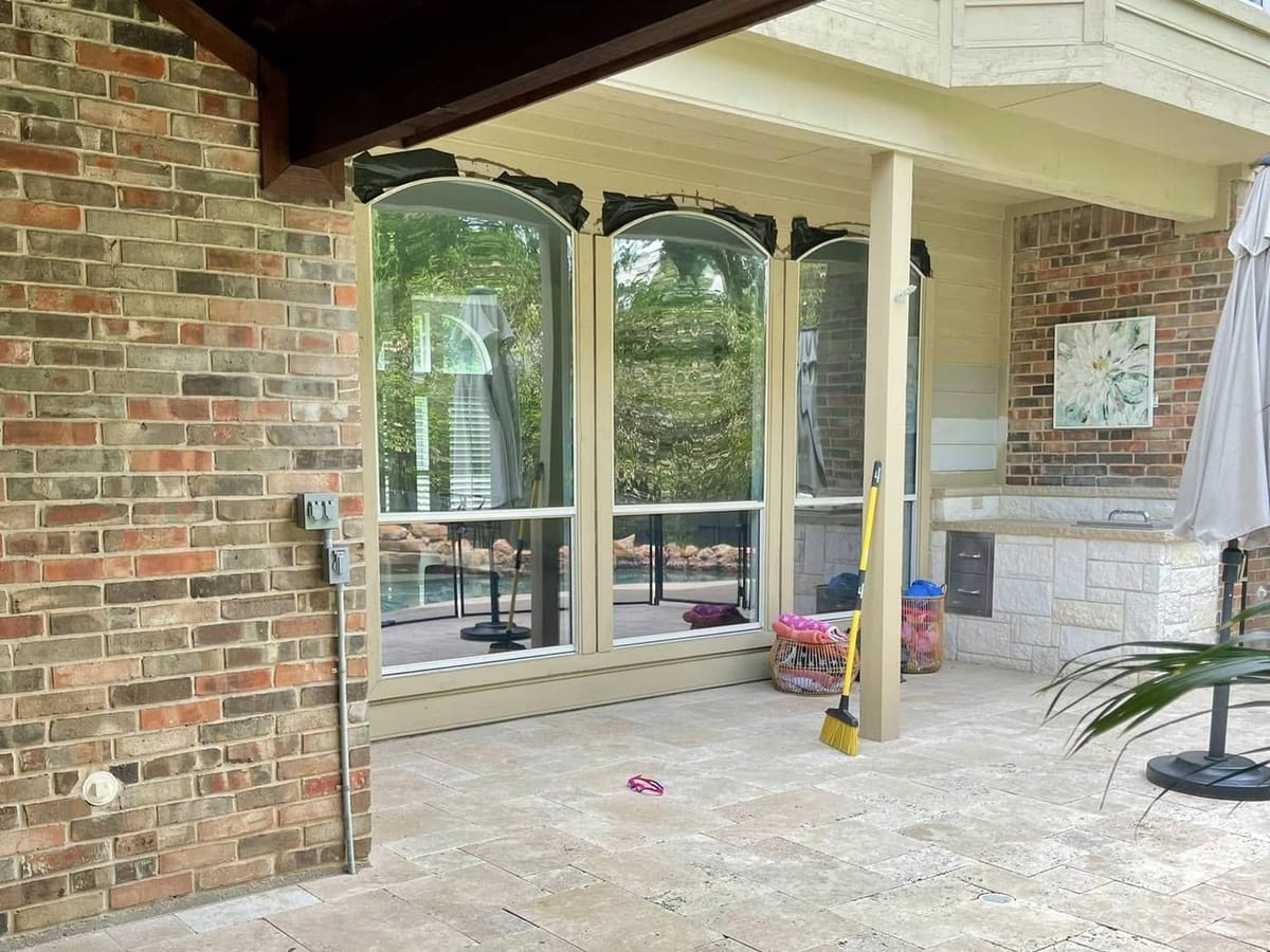 Arched windows on a covered patio, taped across the head, with clouded glass.