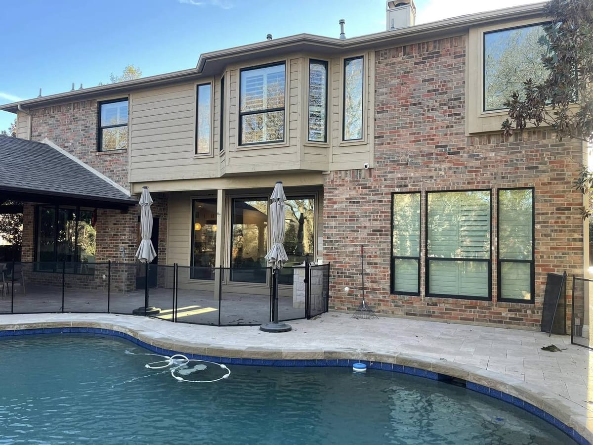 The rear elevation of a two-story brick home after every window was replaced with black-framed units.