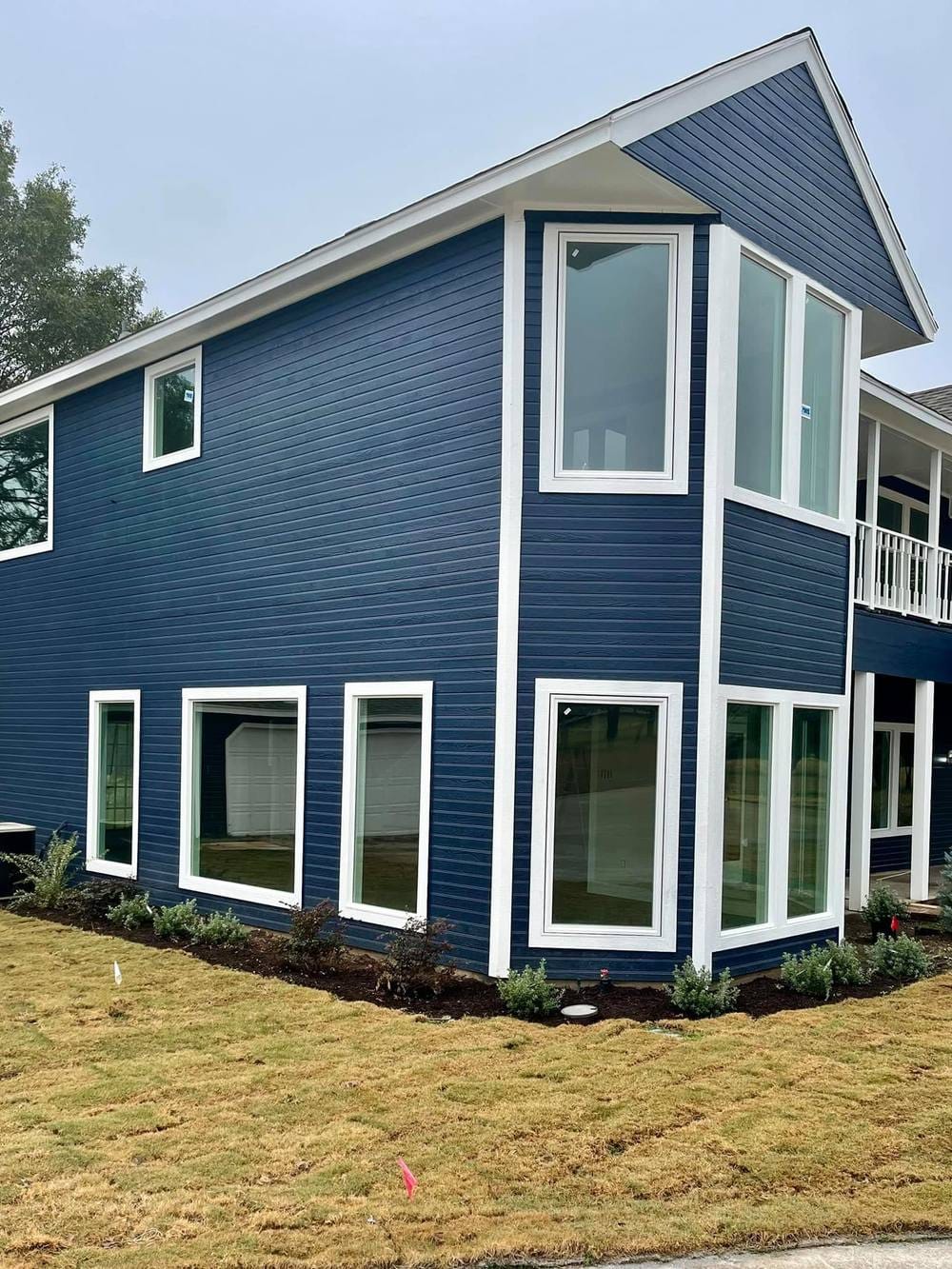 The same home in navy lap siding with new white-framed windows throughout.