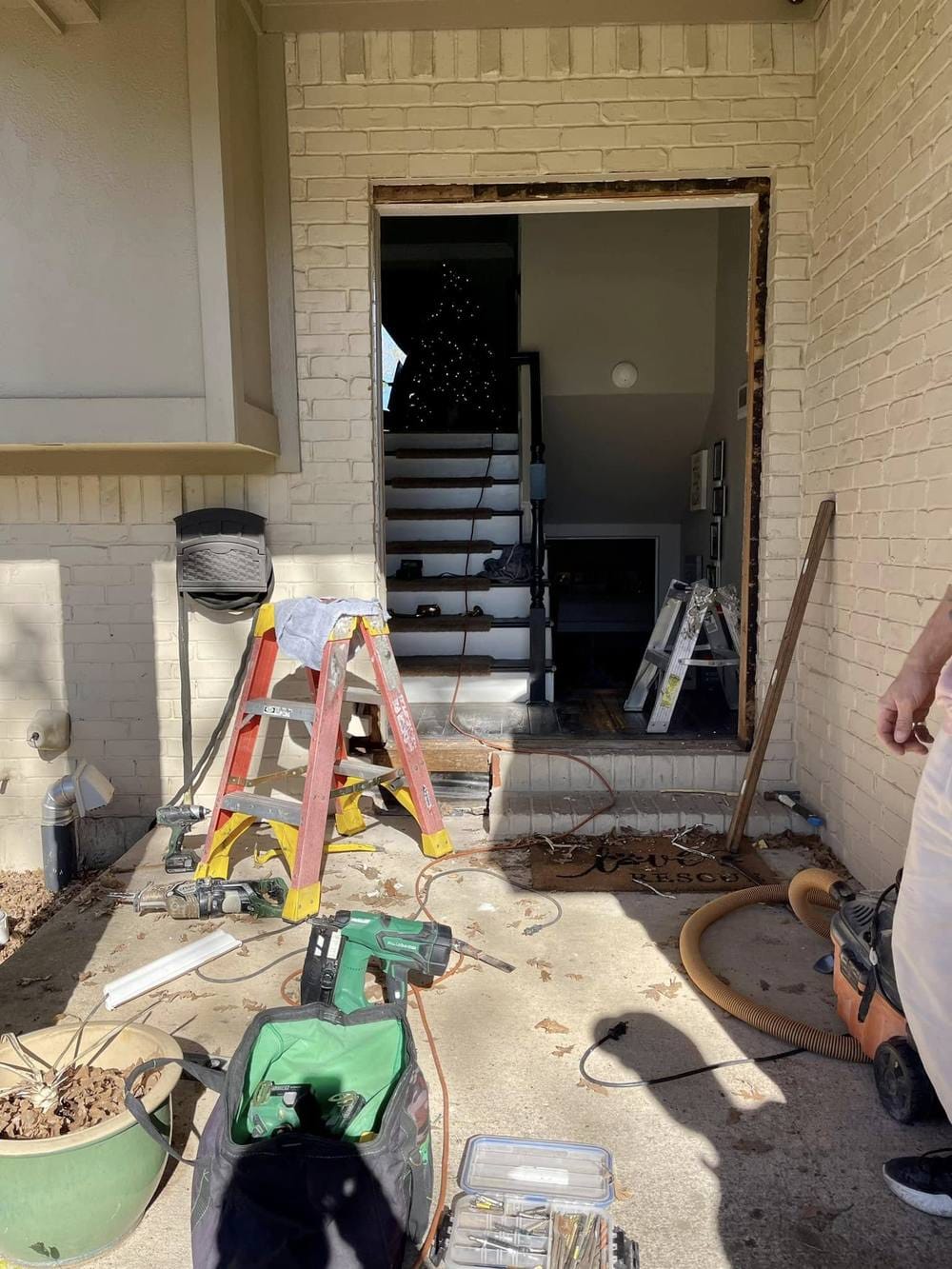The door opening stripped back to the framing, with tools laid out on the porch.